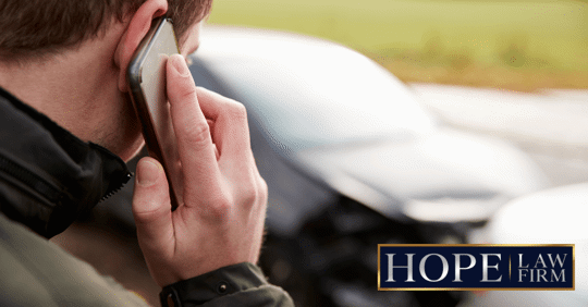 guy looking at car wreck and making a phone call