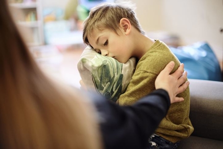 Hand of mother with boy hugging pillow for comfort, compassion and empathy at home.