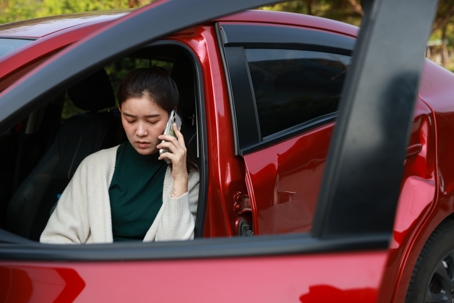 woman on the phone in a dented car
