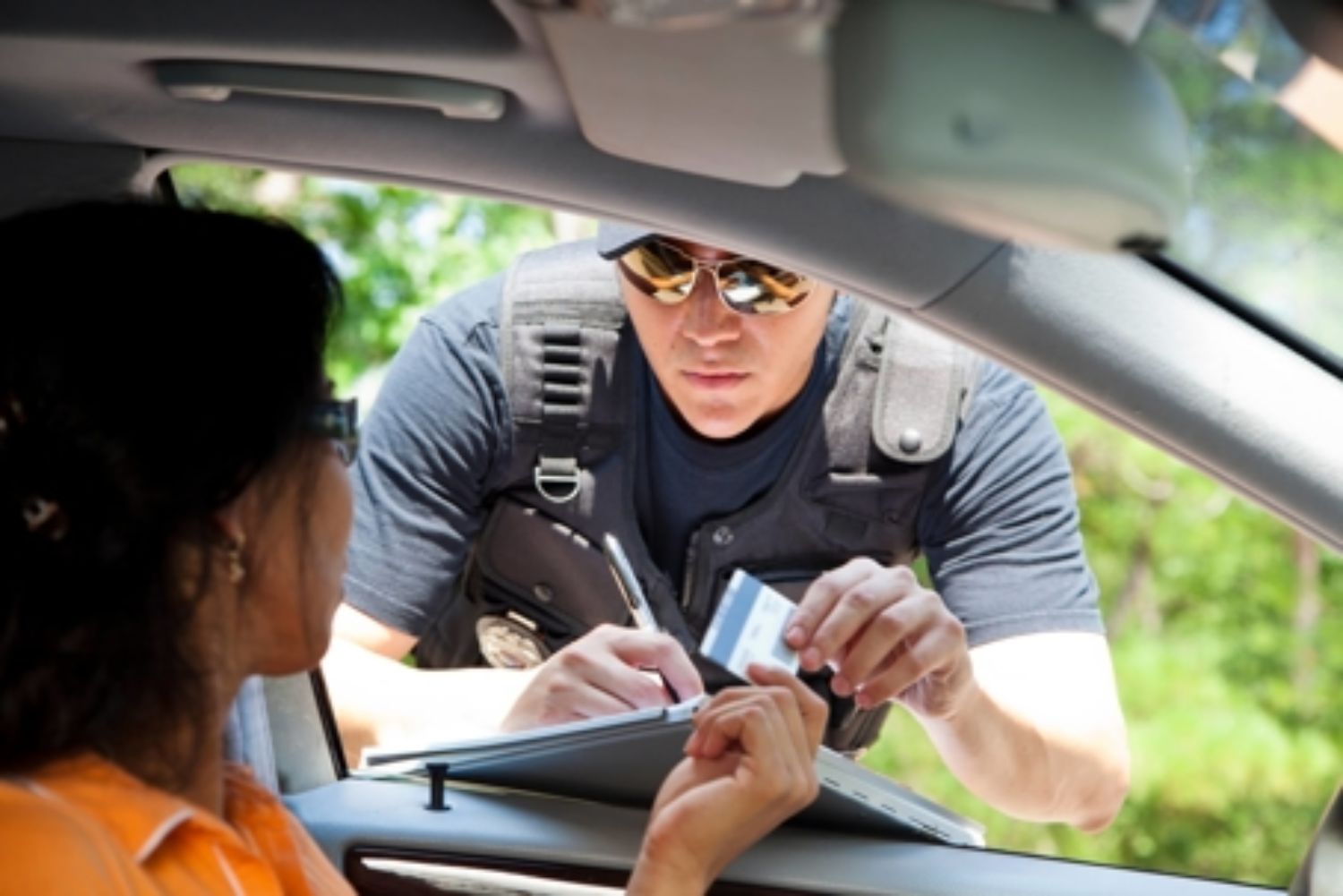 Driver handing police officer license in car