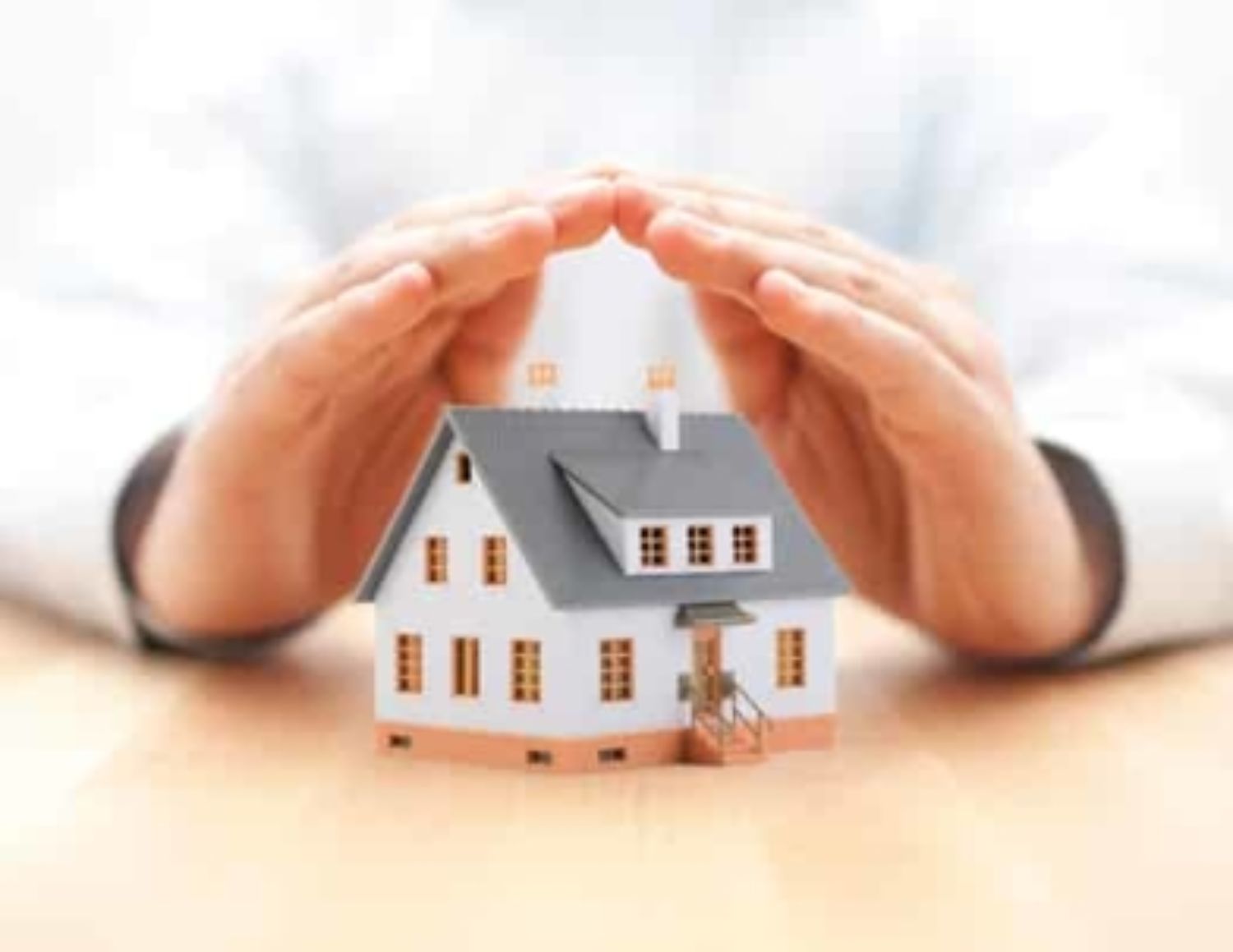 hands protecting toy house
