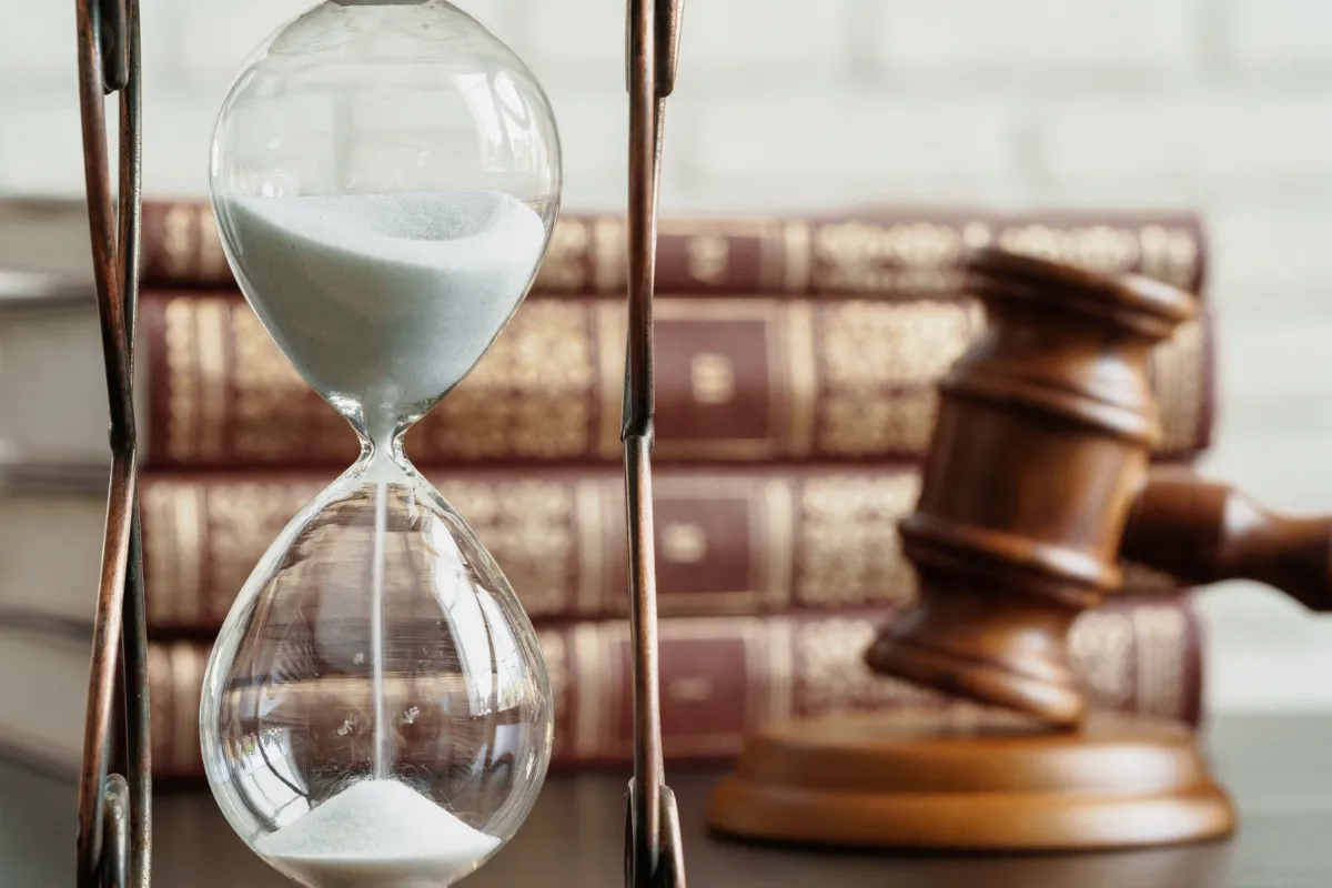 Hourglass beside a judge's gavel and law books